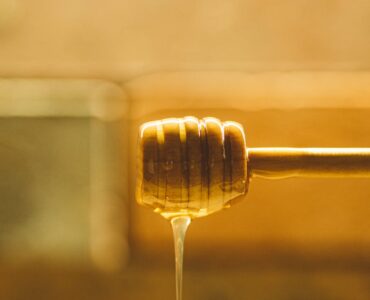 honey dripping from wooden dipper spoon