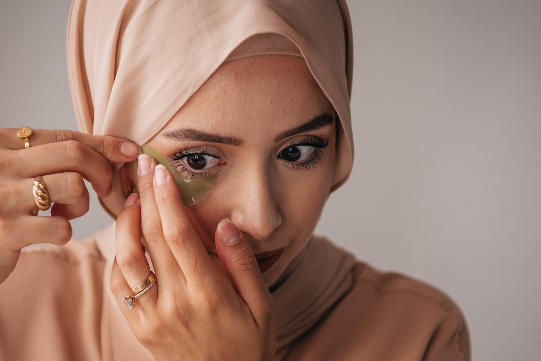 a woman putting an under eye patch